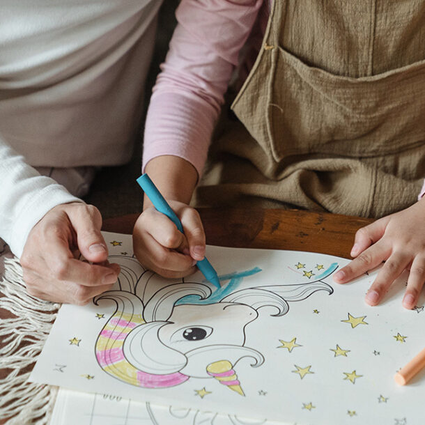 Parent and child hands colouring in a picture of a my little pony