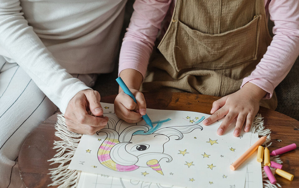 Parent and child hands colouring in a picture of a my little pony